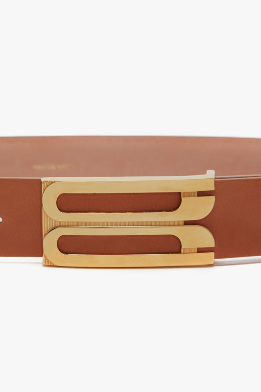 Close-up view of a brown calf leather belt with a unique gold-tone, geometric buckle from Victoria Beckham's Exclusive Jumbo Frame Belt In Nude Leather.
