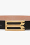 Close-up of a black calf leather Exclusive Jumbo Frame Belt by Victoria Beckham with a detailed gold buckle against a white background.