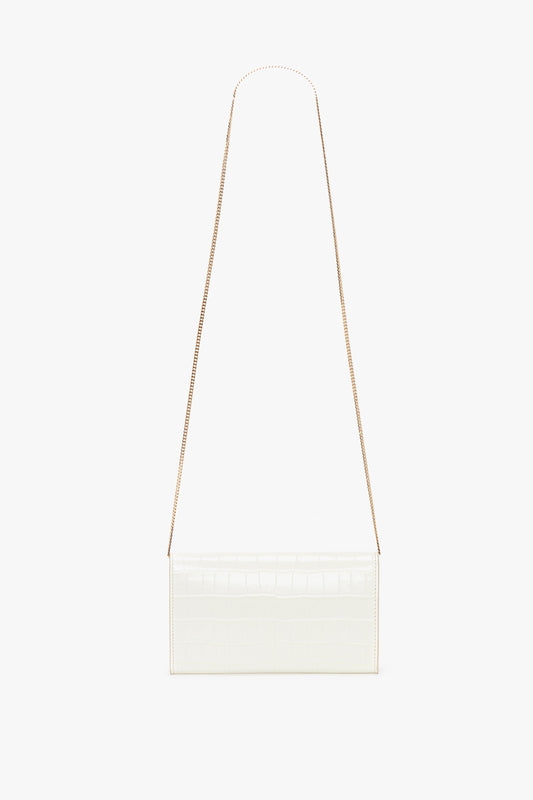 An Exclusive Wallet On Chain In Ivory Croc-Effect Leather, featuring a slender gold chain strap, styled elegantly against a white background. Part of the Victoria Beckham leather goods collection.
