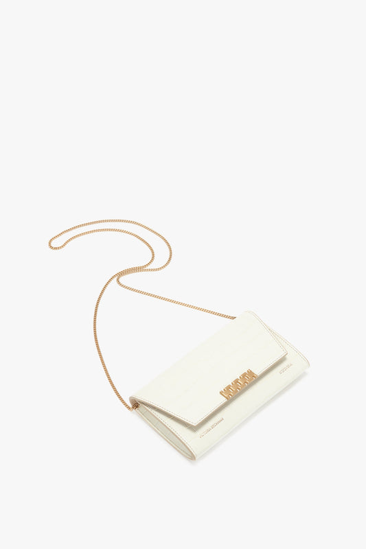 White envelope clutch bag with a gold chain strap, gold accent on the flap, and embossed croc leather detailing. Reminiscent of Victoria Beckham leather goods, this Exclusive Wallet On Chain In Ivory Croc-Effect Leather effortlessly combines elegance and functionality.