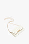 A small white clutch bag with a gold chain strap and a gold clasp featuring the brand name "Victoria Beckham" on the front, doubling as an Exclusive Wallet On Chain In White Leather for added versatility.