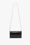 Black rectangular handbag with an embossed croc leather design and a long, golden chain strap, perfect as a stylish **Wallet On Chain In Black Croc-Effect Leather by Victoria Beckham**.