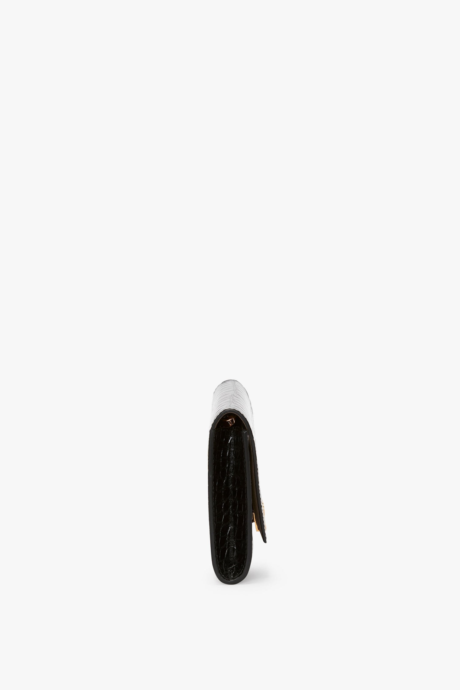 A side view of a folded black leather Wallet On Chain In Black Croc-Effect Leather by Victoria Beckham with visible stitching, enhanced by an elegant golden chain strap, set against a plain white background.