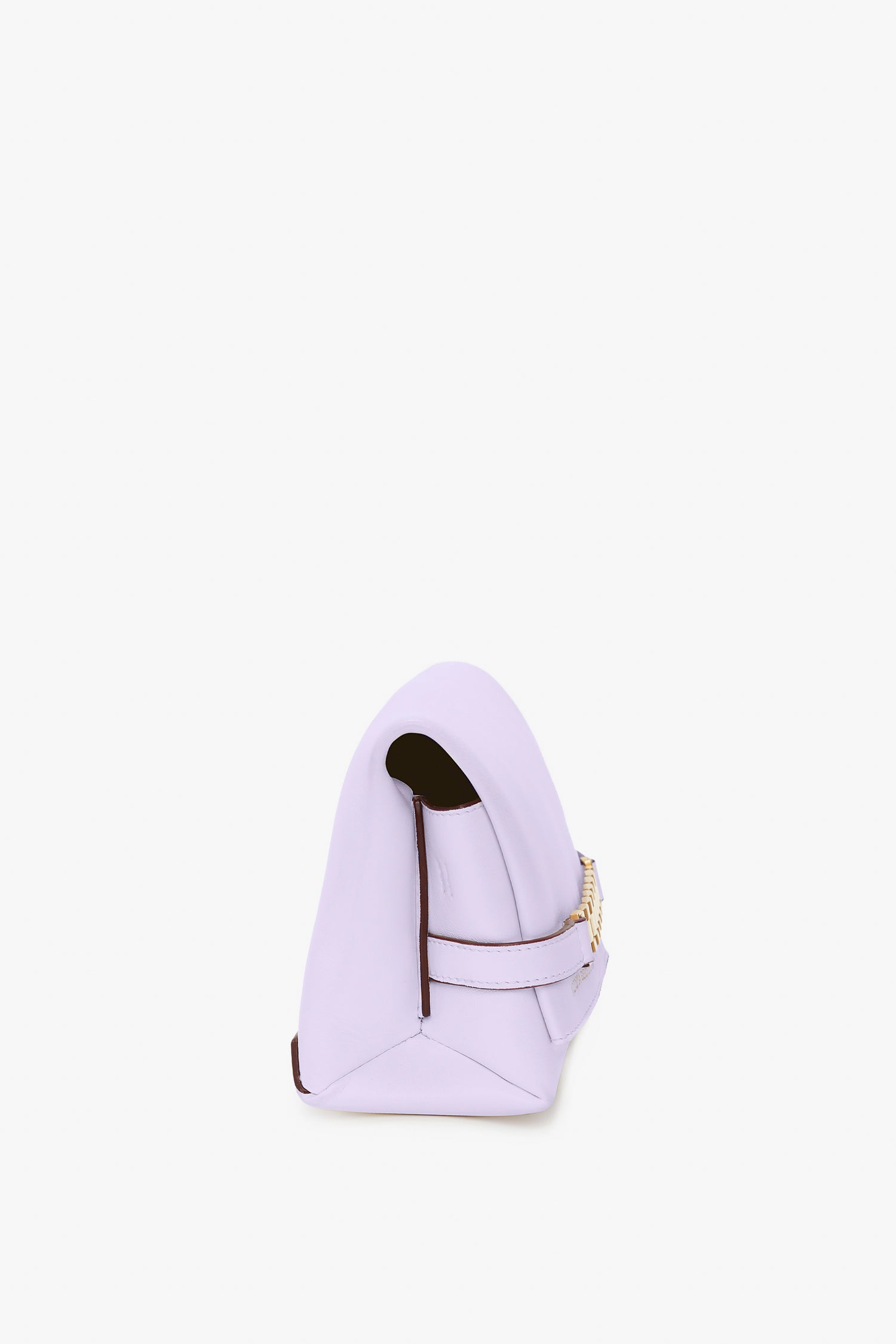 A side view of a light purple Victoria Beckham Exclusive Mini Chain Pouch Bag With Long Strap In Lilac Leather with a folded top and a detachable strap featuring gold hardware. The lilac handbag is placed against a white background.