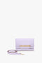 A Victoria Beckham Exclusive Mini Chain Pouch Bag With Long Strap In Lilac Leather with a gold chain detail on the front and a detachable strap placed beside it, set against a plain white background.