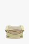 A light green handbag with a beige suede panel and a gold zipper on the front. The bag boasts a structured design, enhanced by its gold chain detail. Timeless and elegant, this Victoria Beckham piece is reminiscent of their Chain Pouch Bag With Strap In Avocado Leather collection.