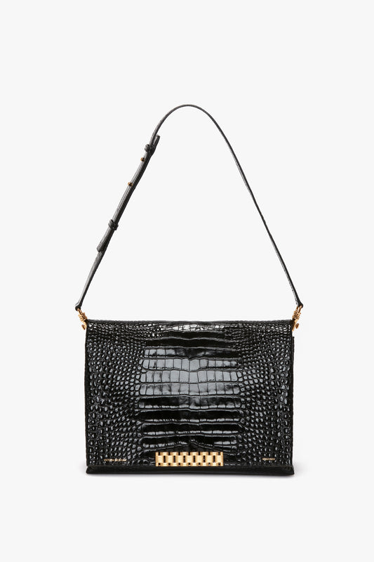 A Victoria Beckham Jumbo Chain Pouch in Black Croc-Effect Leather, featuring a gold clasp and an adjustable shoulder strap, displayed on a white background.