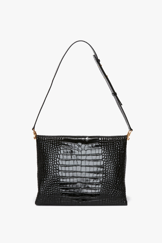 A black, embossed croc leather shoulder bag with a single adjustable strap and gold-toned hardware, displayed against a plain white background has been replaced by the Victoria Beckham Jumbo Chain Pouch in Black Croc-Effect Leather.