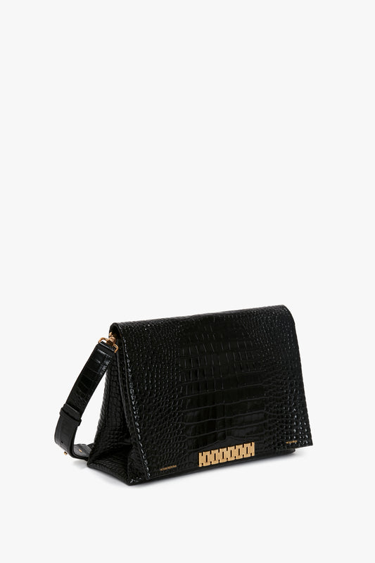 A Victoria Beckham Jumbo Chain Pouch in Black Croc-Effect Leather with a gold-tone clasp and adjustable strap is shown against a plain white background.
