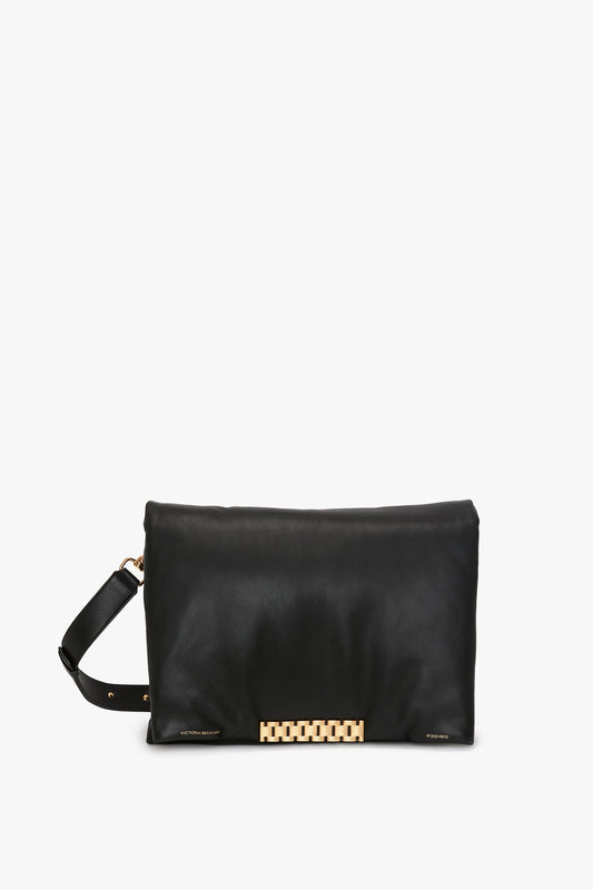 A Puffy Jumbo Chain Pouch In Black Leather from Victoria Beckham with a minimalistic design, featuring a gold-toned geometric clasp and an adjustable shoulder strap against a white background.