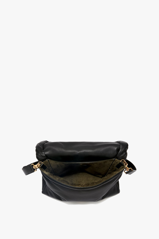 A black sheepskin nappa leather shoulder bag with a gold zipper, open to reveal a beige interior lining, featuring an adjustable shoulder strap for versatile wear has been replaced by the Puffy Jumbo Chain Pouch in Black Leather from Victoria Beckham.