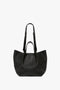 A luxurious grained leather black designer handbag with dual handles and an adjustable strap, featuring a textured finish for versatile styling is the W11 Medium Tote Bag In Black Leather by Victoria Beckham.