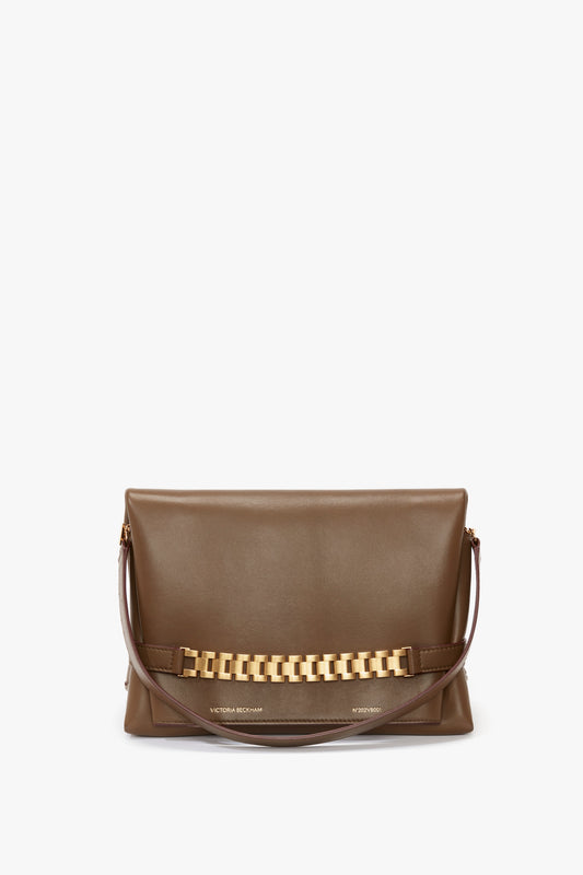 A Chain Pouch Bag With Strap In Khaki Leather by Victoria Beckham featuring a gold chain detail on the front and a detachable brown strap.