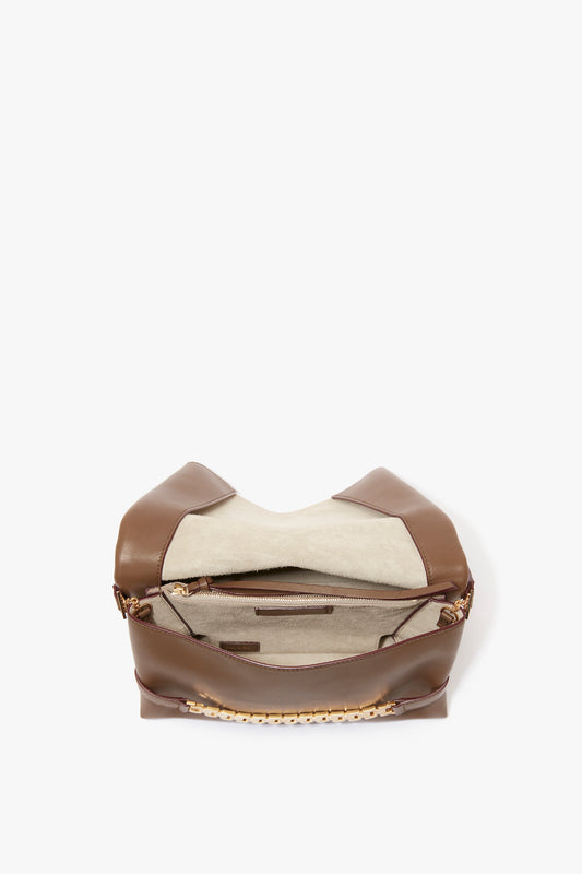 A brown Nappa leather Chain Pouch Bag With Strap In Khaki Leather by Victoria Beckham with an open main compartment revealing a beige interior, a zippered pocket, and a detachable strap.