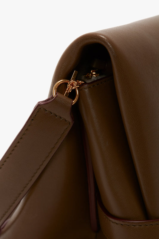 Close-up of a Victoria Beckham Chain Pouch Bag With Strap In Khaki Leather showcasing a gold-tone metal ring attachment where the detachable strap connects to the bag.