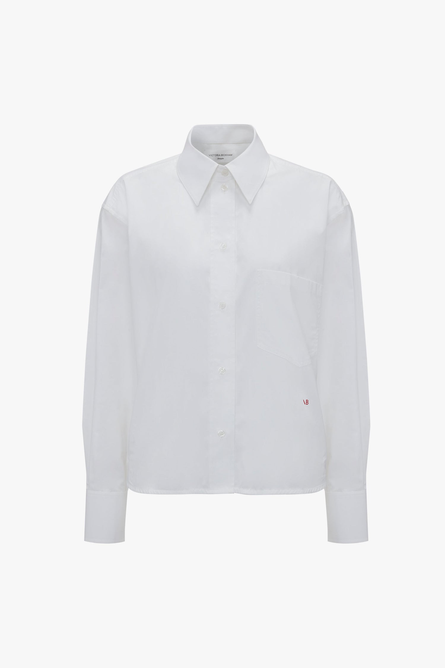 Cropped Long Sleeve Shirt In White with a pointed collar, VB monogram, and a chest pocket, displayed on a plain background by Victoria Beckham.