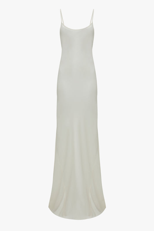 Full-length, off-white Victoria Beckham Floor-Length Cami Dress In Ivory with thin spaghetti straps displayed on a plain white background, evoking 90s fashion elegance.