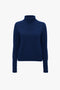 A plain, navy blue Polo Neck Jumper In Navy by Victoria Beckham with a lambswool polo neck and long sleeves, set against a white background.