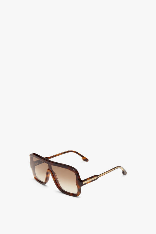 A pair of Victoria Beckham Layered Mask Sunglasses In Tortoise-Brown with an iconic visor silhouette and rectangular lens featuring a gradient tint, angled slightly upward on a plain white background.