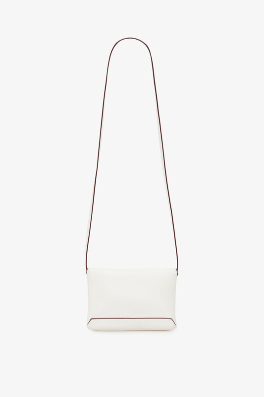 A minimalist white crossbody bag with a long, thin strap and a small rectangular body. The edges of the Victoria Beckham-inspired bag have subtle dark piping. The Mini Chain Pouch Bag With Long Strap In White Leather by Victoria Beckham comes with a removable strap for versatile styling options against the plain white background.