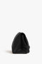 A Victoria Beckham Chain Pouch Bag In Black Leather with a visible chain strap, standing upright on a white background.