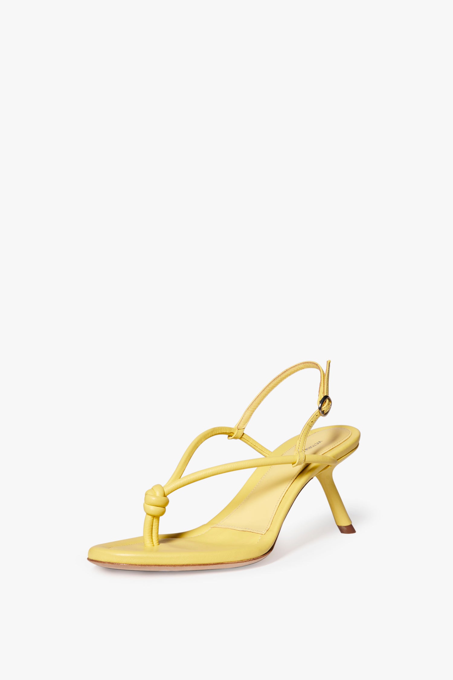 The Victoria Beckham Estelle in Pale Yellow, a pale yellow nappa leather high-heeled sandal with a knot detail, almond toe, and a slingback strap against a white background.