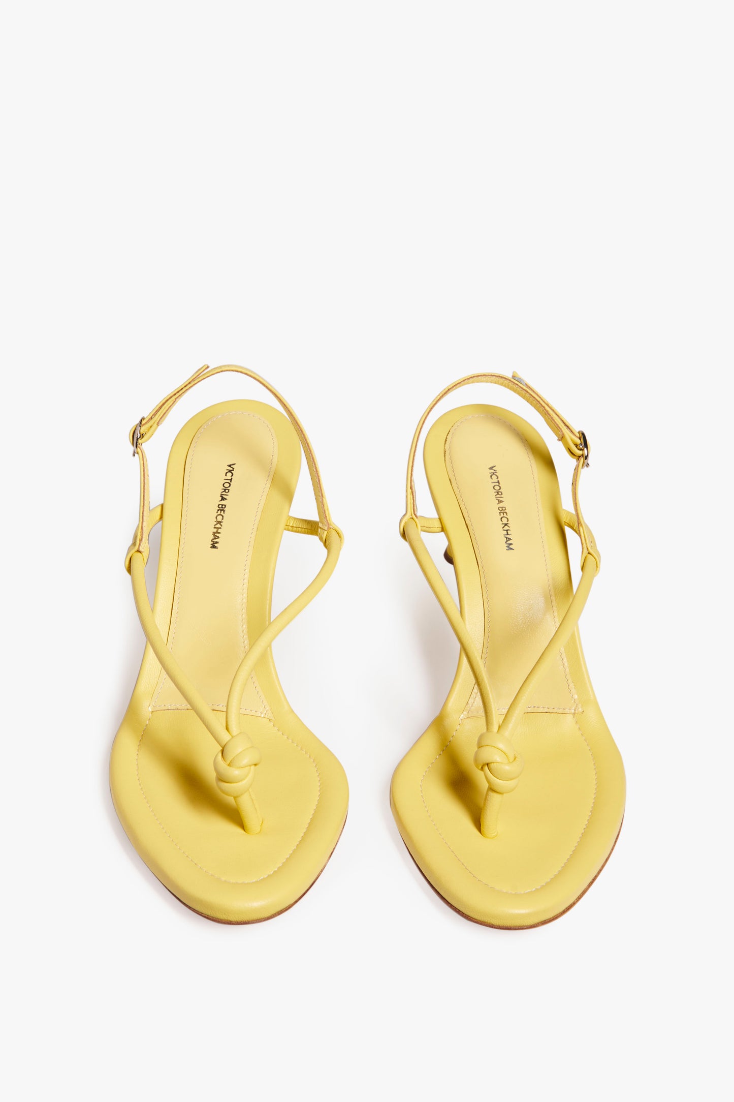 A pair of Estelle in Pale Yellow by Victoria Beckham with thin, tubular straps, a knotted design at the toes, and ankle straps.