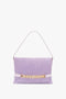 A Chain Pouch Bag with Strap in Lilac Suede by Victoria Beckham crafted from Italian leather with a gold chain detail on the front and a single strap.