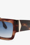 Close-up view of tortoiseshell Victoria Beckham V Plaque Frame Sunglasses In Dark Brown Horn with blue lenses and a gold-colored metallic accent near the hinge.