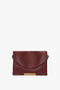 A Jumbo Chain Pouch Bag In Bordeaux by Victoria Beckham with a gold clasp and detachable shoulder strap.