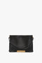 Victoria Beckham's Jumbo Chain Pouch Bag In Black Leather with a gold-tone chain detail on the front, a single strap, and a minimalist design.