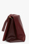 A Jumbo Chain Pouch Bag In Bordeaux with a slouchy, folded design and a metallic clasp on the detachable strap, viewed from the side against a plain white background.