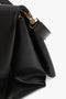 Close-up of a Victoria Beckham Jumbo Chain Pouch Bag In Black Leather with a gold clasp, gold-tone chain detail, and a leather strap.