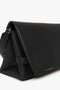 A black Nappa leather Chain Pouch Bag with Strap In Black Leather by Victoria Beckham with a folded flap design and a small gold brand inscription on the bottom right corner. The clutch also features a detachable handle for versatile carrying options.