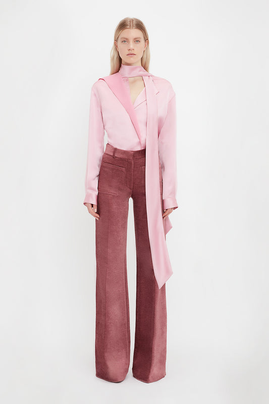 Model wears the Alina tailored women's trousers from luxury fashion designer Victoria Beckham. The tailored wide leg trousers come in a 70s flared style in a plum colour.