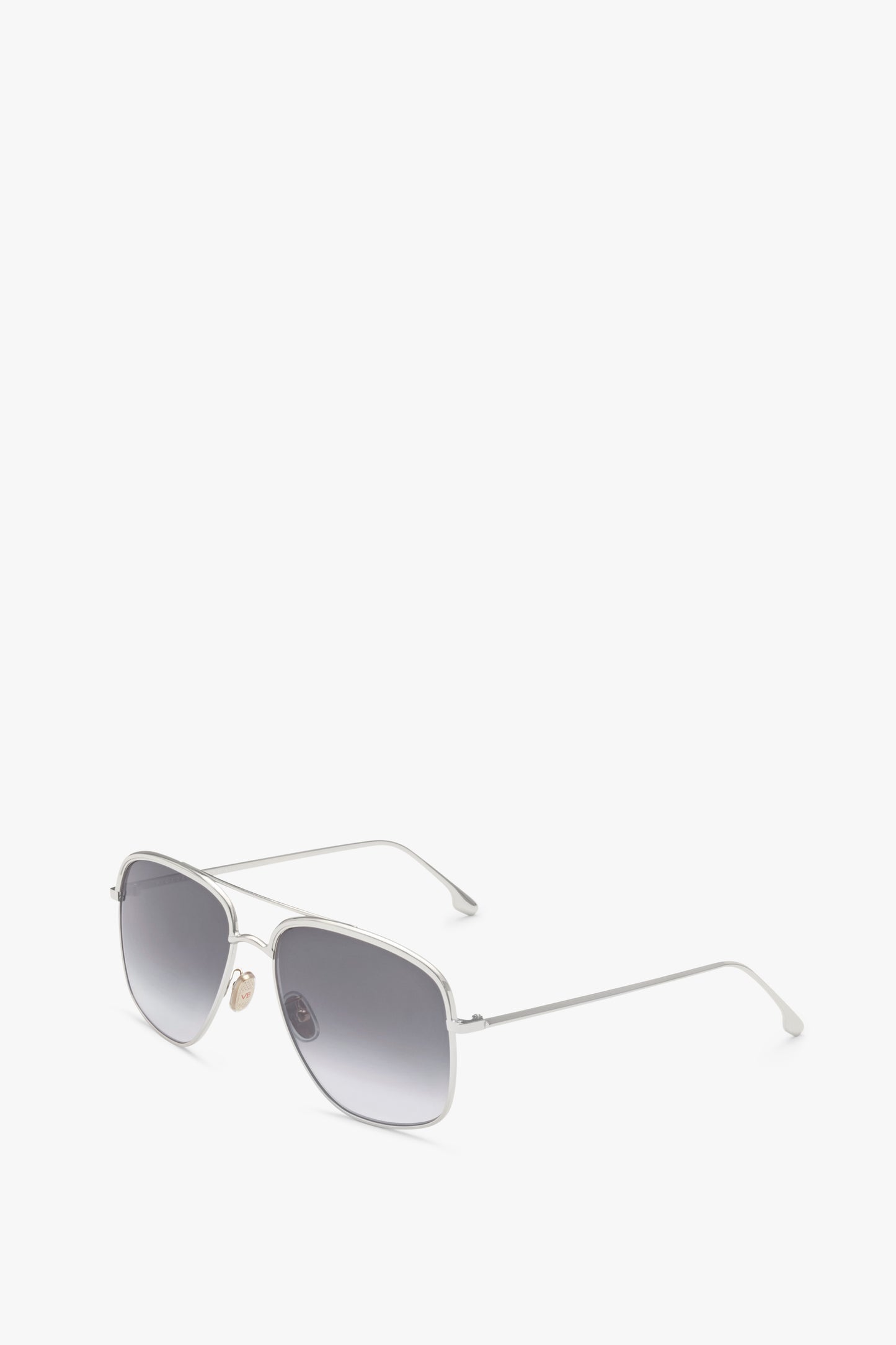 A pair of handcrafted in Italy, silver-framed, rectangular sunglasses with dark tinted Zeiss lenses and thin arms, placed against a plain white background. 

Replacement:
A pair of Double Brow Navigator in Silver by Victoria Beckham, silver-framed, rectangular sunglasses with dark tinted Zeiss lenses and thin arms, placed against a plain white background.